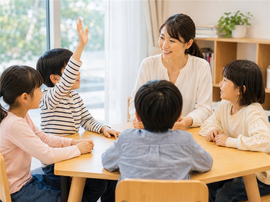少人数で手を挙げて発言する子どもたちと先生